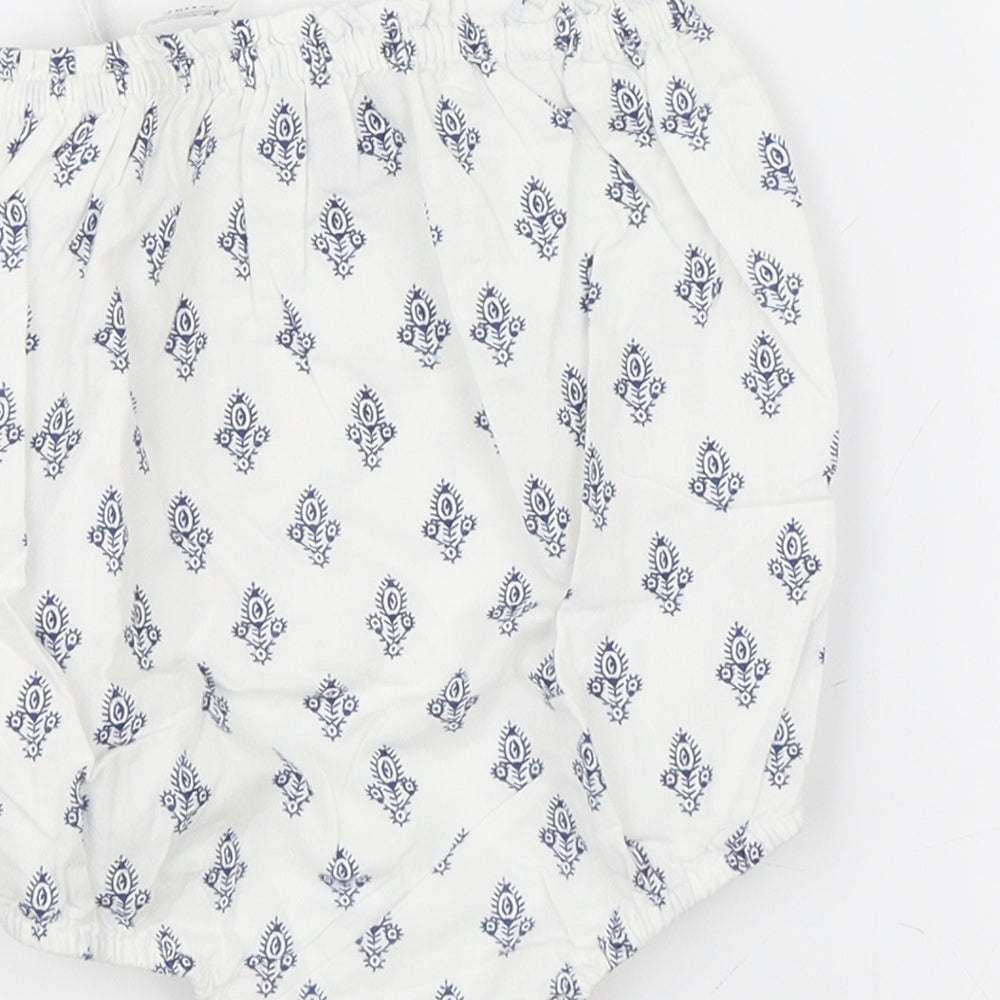 Brand and care label for Baby Gap girls’ white paisley leotard one-piece, size 6-9, months