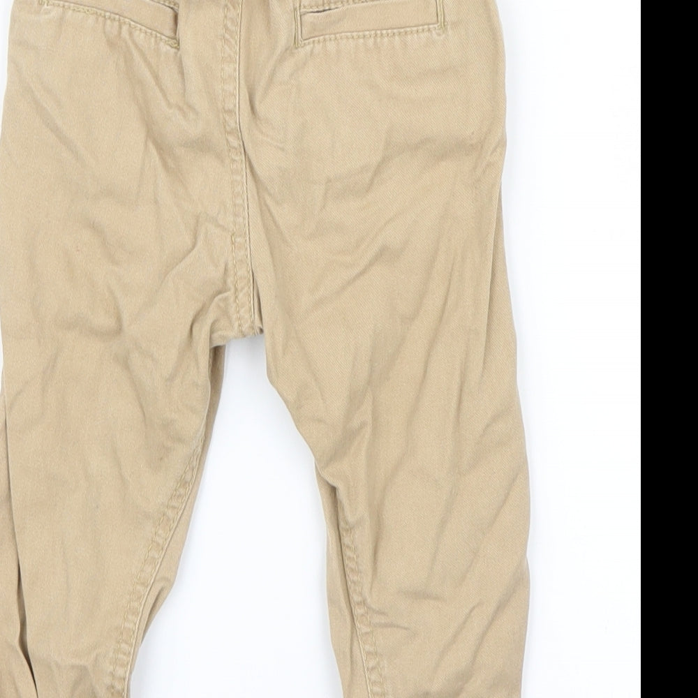 Brand and care label for Little Rebel boys’ beige capri trousers, size 18-24, months