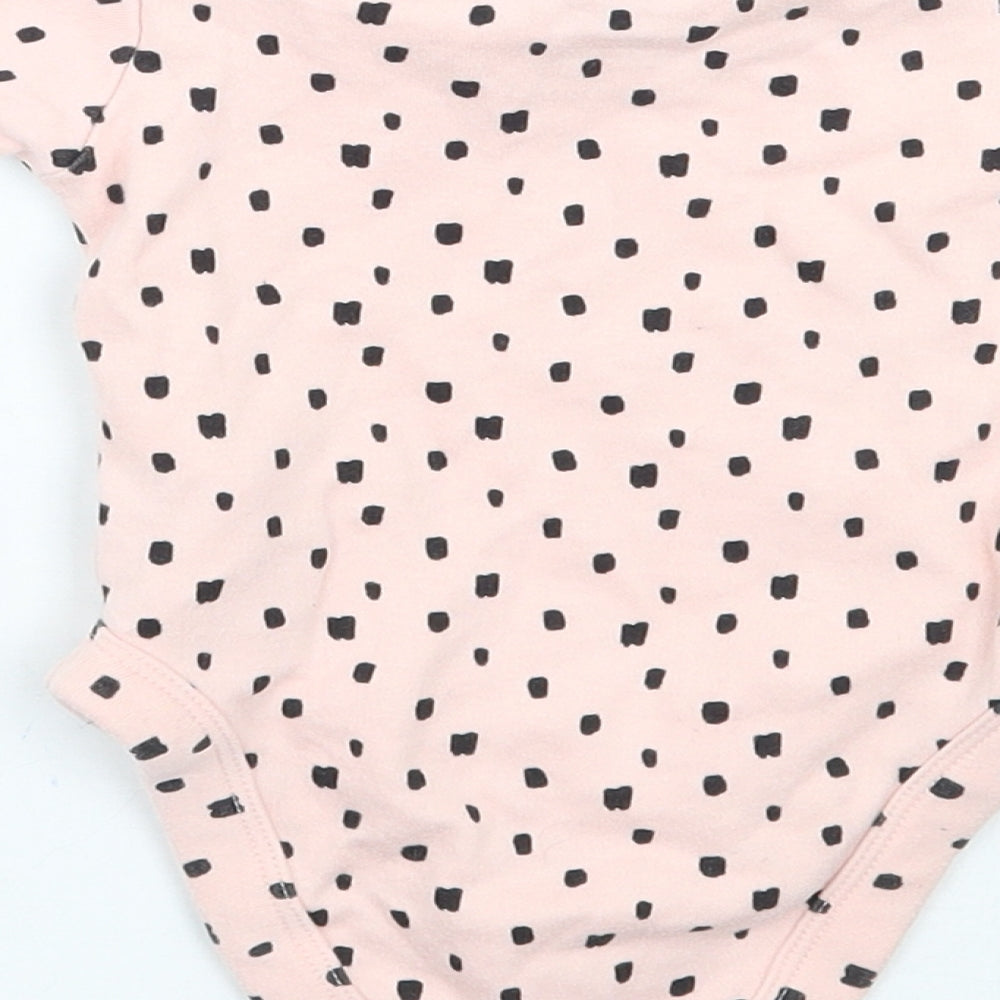 Brand and care label for Primark girls’ pink geometric babygrow one-piece, size 0-3, months