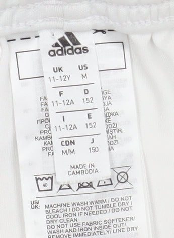 Brand and care label for Adidas boys’ white athletic football shorts, size 11-12y