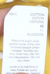 Brand and care label for Gap girls’ yellow polka dot t-shirt, size 10-11, cotton, spring