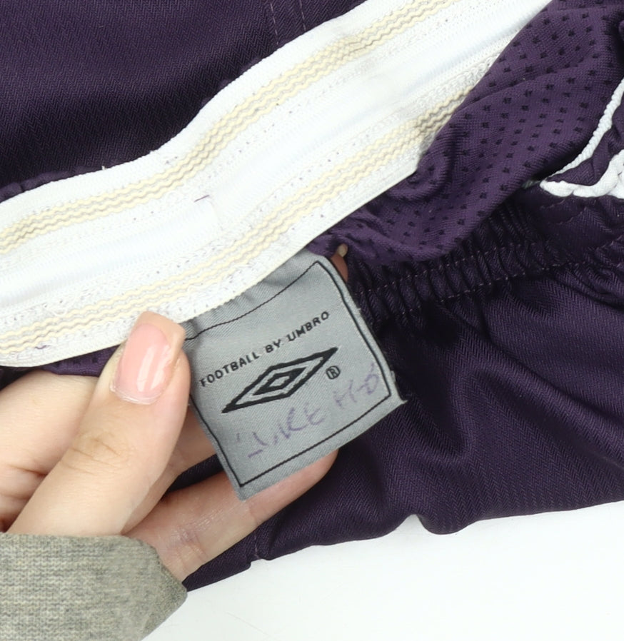 Brand and care label for Umbro boys’' purple athletic football shorts, size 158