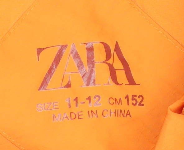 Close-up detail of Zara girls’ orange puffer jacket 11-12 years sleeveless