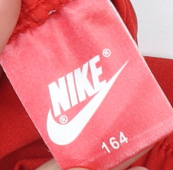 Brand and care label for Nike boys’ red athletic football shorts, size 164, breathable activewear