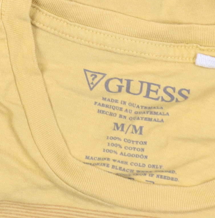 Brand and care label for Guess men’s yellow graphic logo t-shirt, size M, cotton crew neck