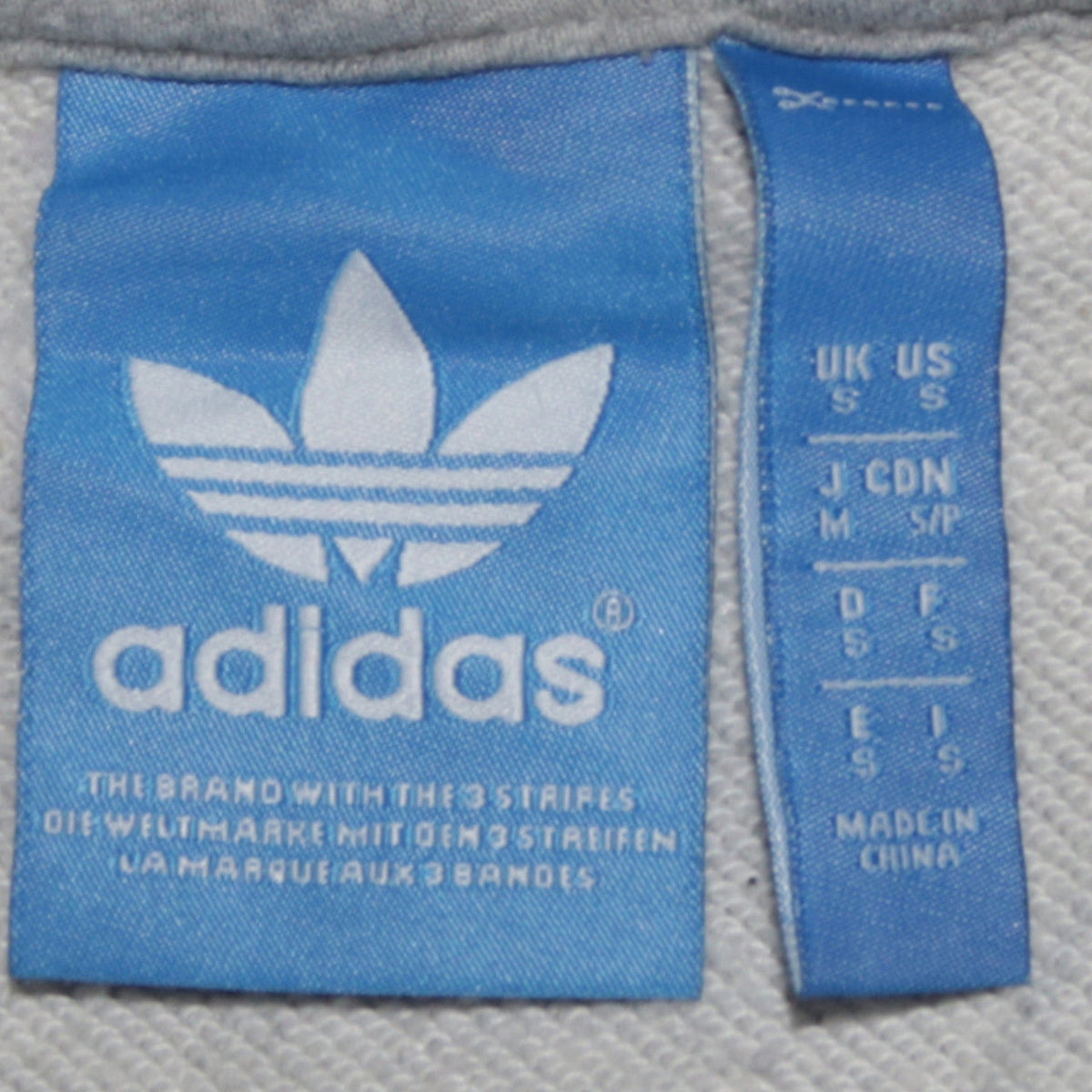 Close-up detail of Adidas men’s grey pullover hoodie small logo sportswear fleece