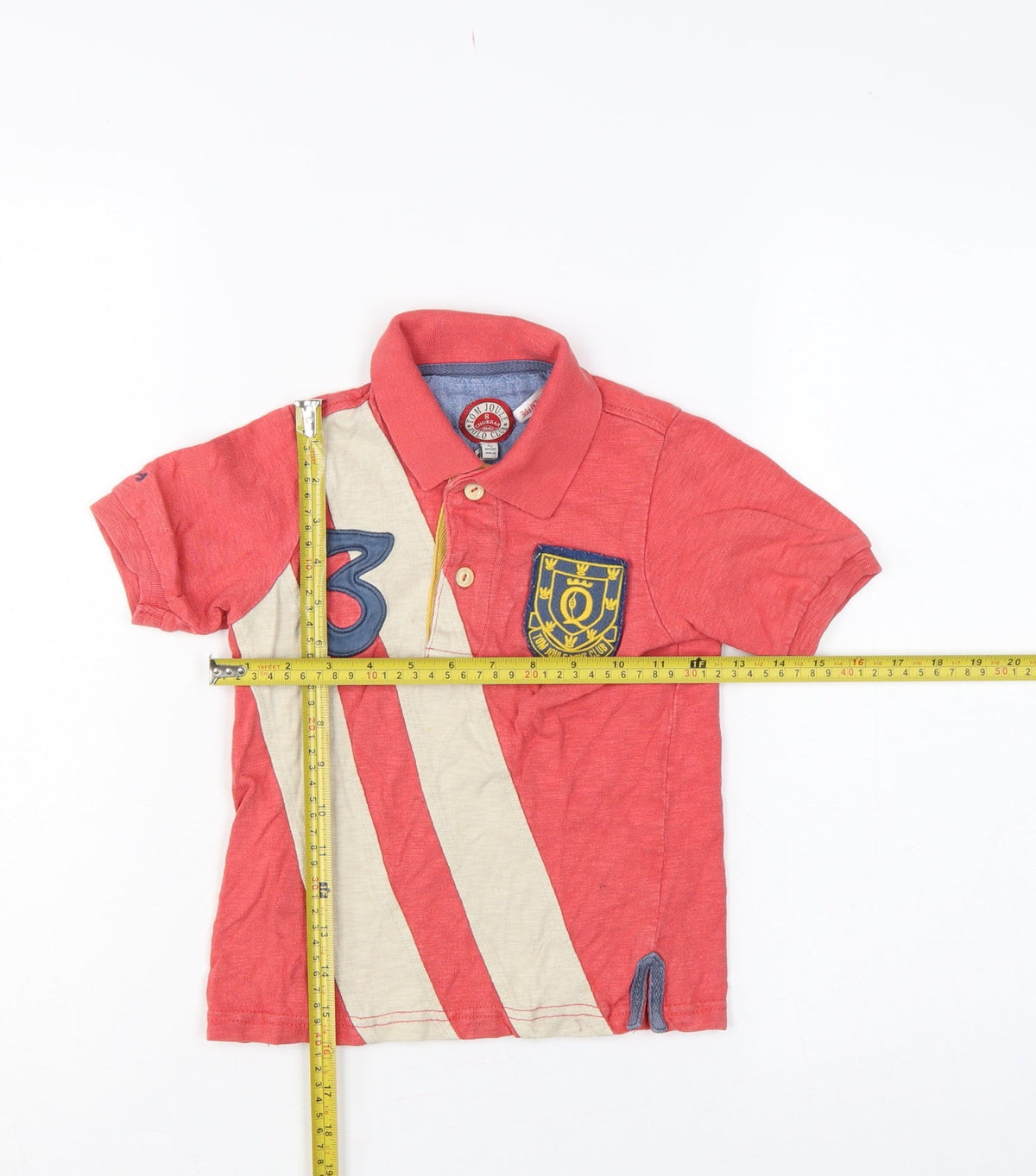 Close-up detail of Tom Joule boys’ red 4 years striped logo crest short sleeve polo shirt