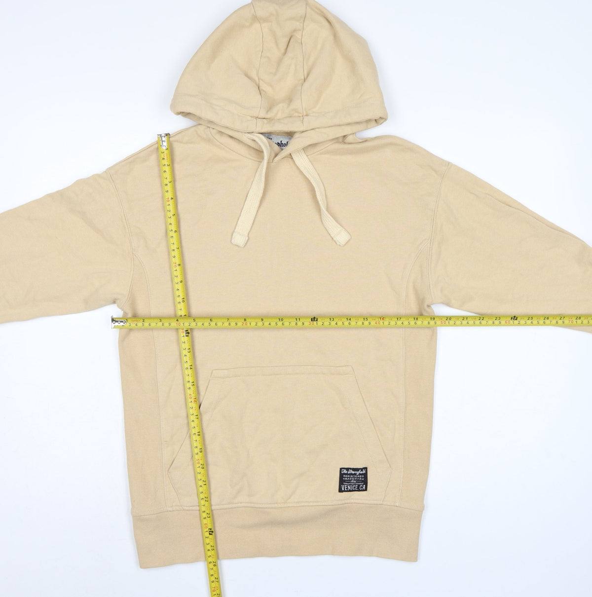 Close-up detail of The Stronghold Men’s Beige XS Pullover Hoodie Venice CA Logo